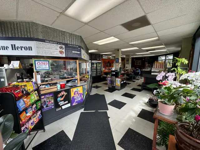 Inside Blue Heron: checkerboard floor, hand-lettered menu boards over the deli counter, and orchids by the window